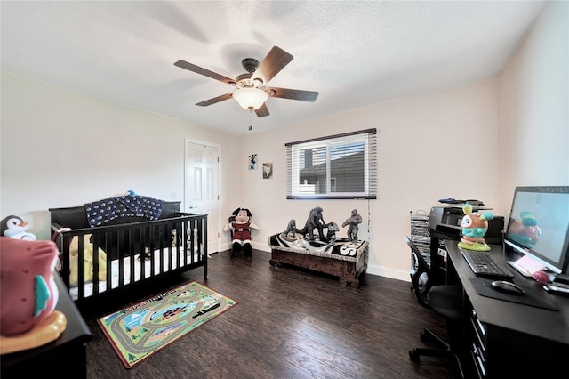 bedroom featuring a crib, dark wood-type flooring, a textured ceiling, and ceiling fan