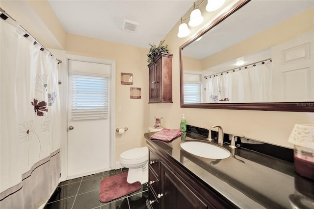 bathroom with vanity, a healthy amount of sunlight, tile patterned floors, and toilet