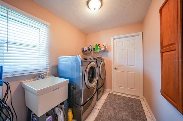 washroom featuring sink, light tile patterned floors, washing machine and dryer, and a textured ceiling