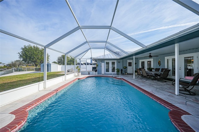 view of pool with a patio, a yard, glass enclosure, ceiling fan, and french doors