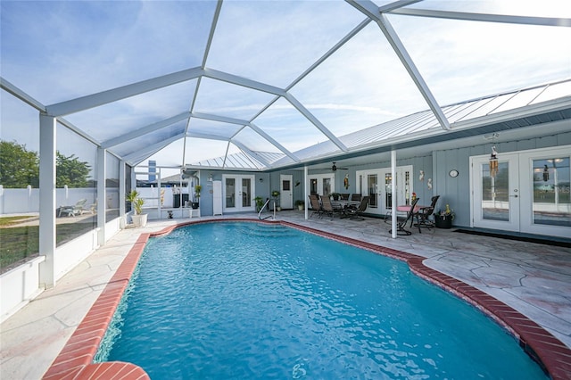 view of swimming pool featuring a patio area, glass enclosure, and french doors