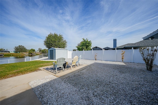 view of yard with a water view, a shed, and a patio area