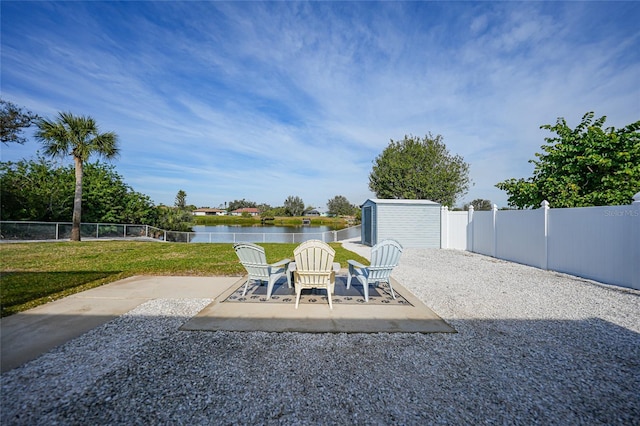 view of patio with a shed and a water view