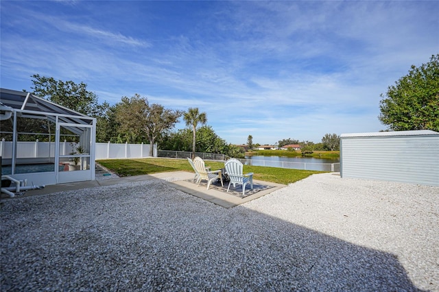 view of yard featuring a water view, a patio area, and glass enclosure