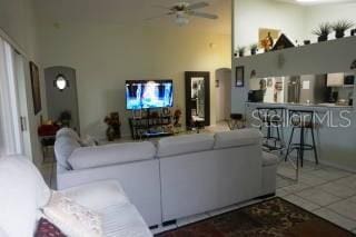 tiled living room featuring ceiling fan and a towering ceiling