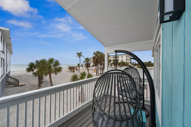 balcony with a water view and a view of the beach