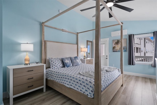 bedroom with hardwood / wood-style flooring, vaulted ceiling, a wall unit AC, and ceiling fan