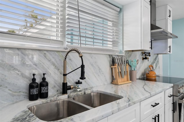 kitchen featuring wall chimney exhaust hood, sink, white cabinetry, stainless steel electric range, and light stone countertops