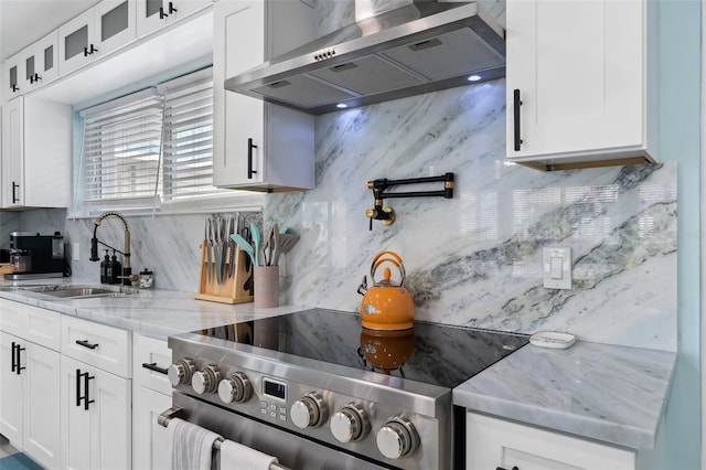 kitchen with wall chimney exhaust hood, sink, white cabinetry, tasteful backsplash, and stainless steel electric range oven