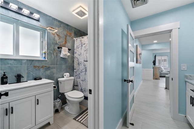 bathroom with vanity, plenty of natural light, tile walls, and toilet