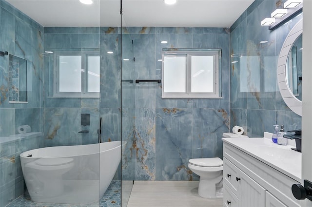 bathroom featuring tile walls, a tub to relax in, vanity, and toilet