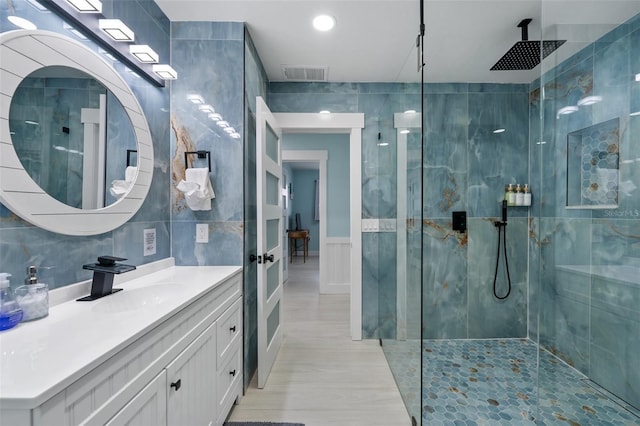 bathroom featuring tile walls, vanity, and a tile shower