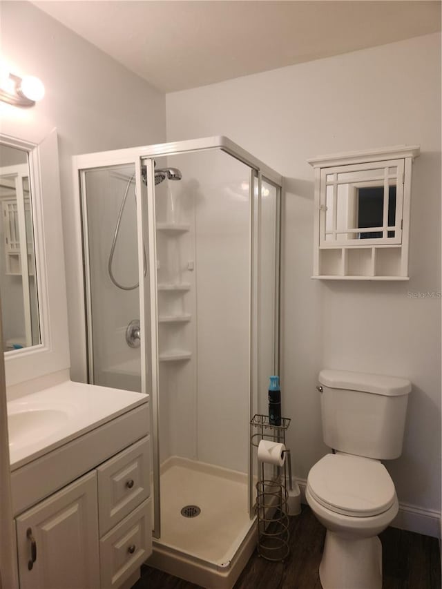 bathroom with a shower with door, vanity, hardwood / wood-style floors, and toilet