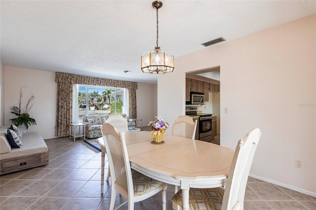 tiled dining room featuring a notable chandelier and a textured ceiling