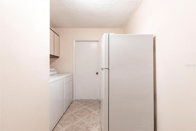 washroom with independent washer and dryer, cabinets, light tile patterned flooring, and a textured ceiling