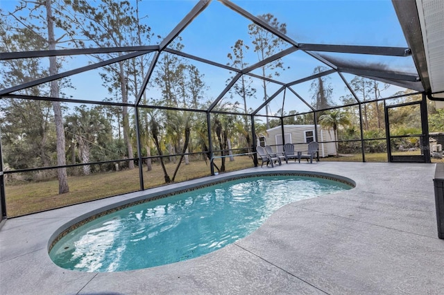 view of swimming pool featuring a storage shed, a patio area, and glass enclosure