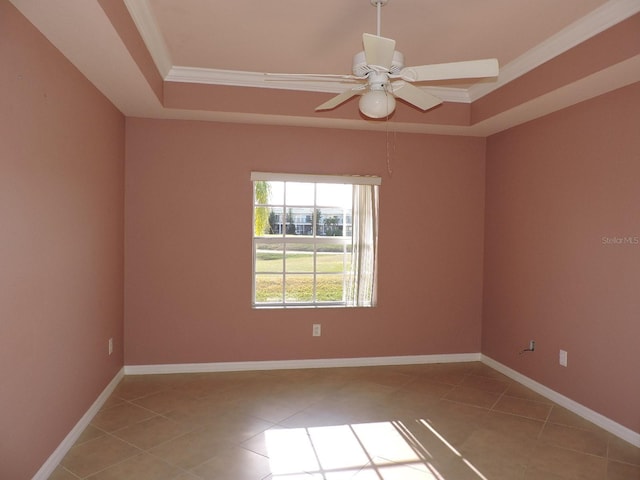 unfurnished room featuring a tray ceiling, ornamental molding, and light tile patterned flooring