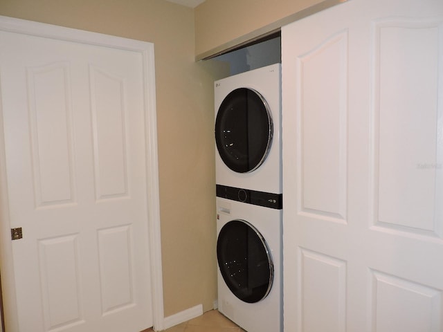 washroom featuring stacked washer and dryer and light tile patterned floors