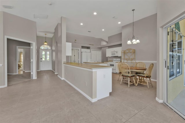 kitchen featuring white cabinetry, kitchen peninsula, a notable chandelier, pendant lighting, and white appliances