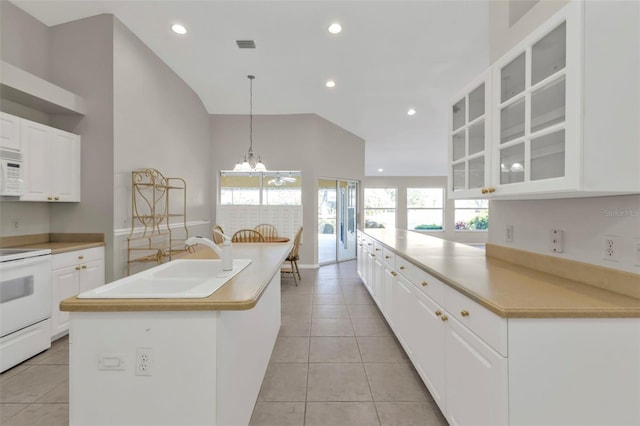 kitchen with white cabinetry, range, light tile patterned floors, and a center island with sink