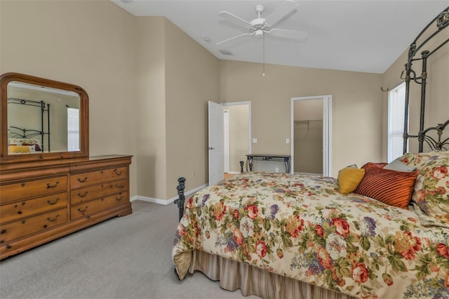 carpeted bedroom featuring a walk in closet, vaulted ceiling, a closet, and ceiling fan