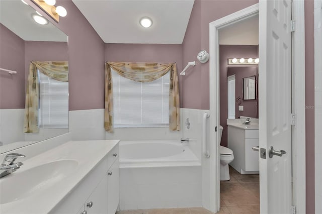 bathroom with toilet, tile patterned floors, tiled bath, and vanity