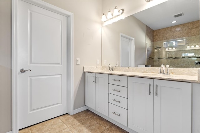 bathroom with tile patterned flooring, vanity, and a tile shower