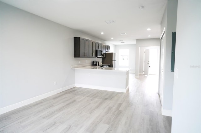 kitchen with stainless steel appliances, kitchen peninsula, and light hardwood / wood-style floors