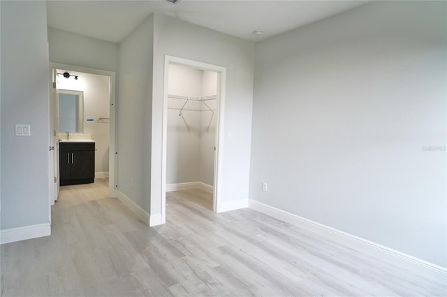 unfurnished bedroom with a walk in closet, light wood-type flooring, and a closet