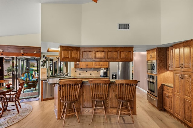 kitchen with a center island, appliances with stainless steel finishes, a kitchen breakfast bar, a towering ceiling, and backsplash