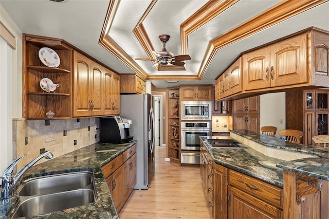 kitchen featuring sink, light wood-type flooring, a raised ceiling, ceiling fan, and stainless steel appliances