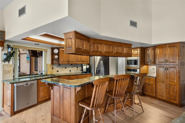 kitchen with sink, appliances with stainless steel finishes, a kitchen breakfast bar, a kitchen island, and dark stone counters