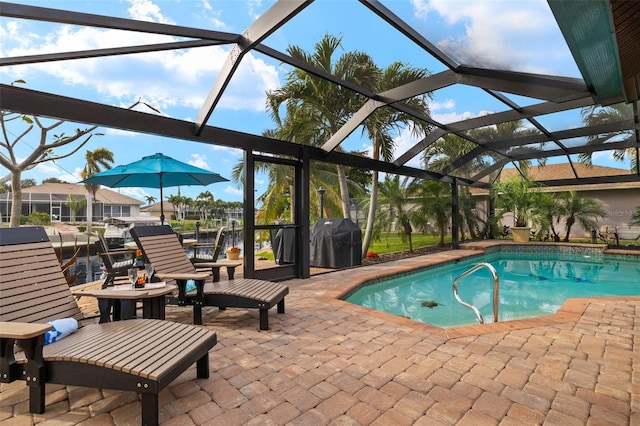 view of pool featuring a grill, a patio, and glass enclosure