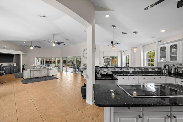 kitchen featuring white cabinetry, dark stone countertops, black electric stovetop, and backsplash