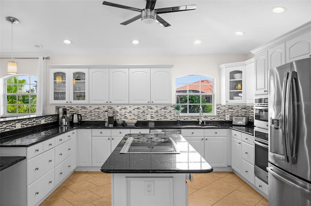 kitchen with sink, white cabinetry, hanging light fixtures, a kitchen island, and stainless steel appliances