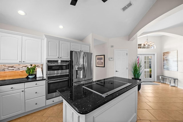 kitchen with white cabinetry, dark stone countertops, decorative backsplash, hanging light fixtures, and stainless steel appliances