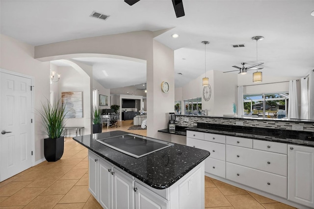 kitchen featuring a kitchen island, white cabinets, hanging light fixtures, black electric stovetop, and ceiling fan