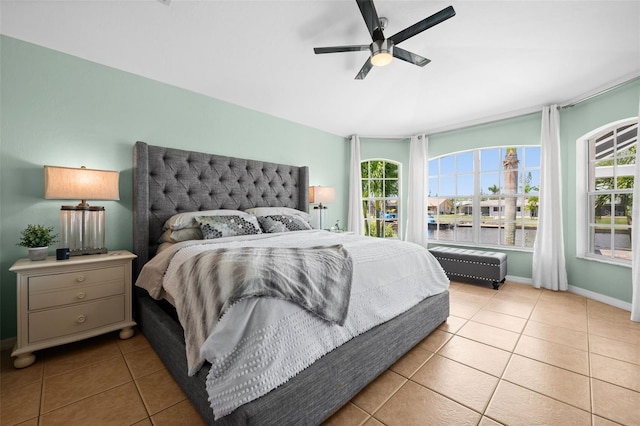 bedroom featuring a water view, ceiling fan, and light tile patterned floors