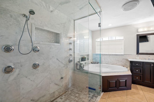 bathroom with vanity, independent shower and bath, tile patterned flooring, and tile walls