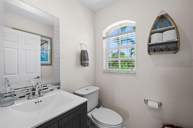 bathroom featuring vanity, backsplash, and toilet