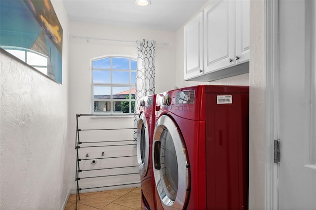 laundry room featuring independent washer and dryer, light tile patterned floors, cabinets, and a healthy amount of sunlight