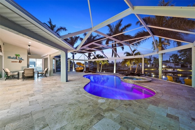 pool at dusk with a lanai, a patio area, and an in ground hot tub