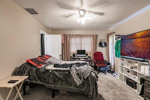 carpeted bedroom with ceiling fan and a textured ceiling