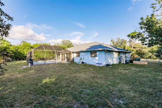 rear view of property with a lanai, a yard, and central AC unit