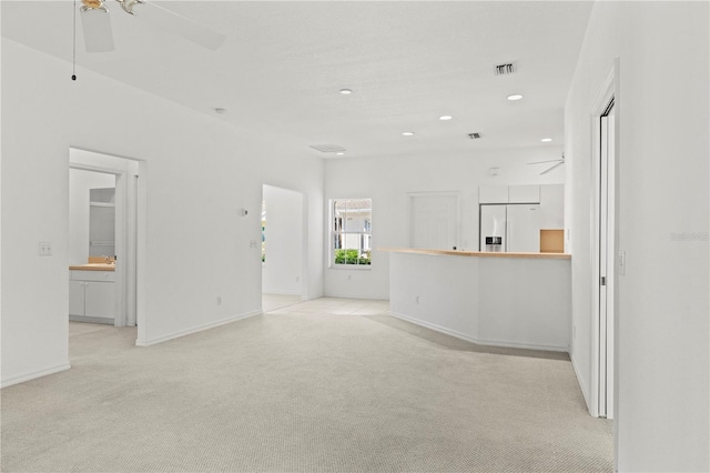 unfurnished living room featuring light colored carpet and ceiling fan