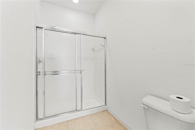 bathroom with tile patterned flooring, a shower with door, and toilet