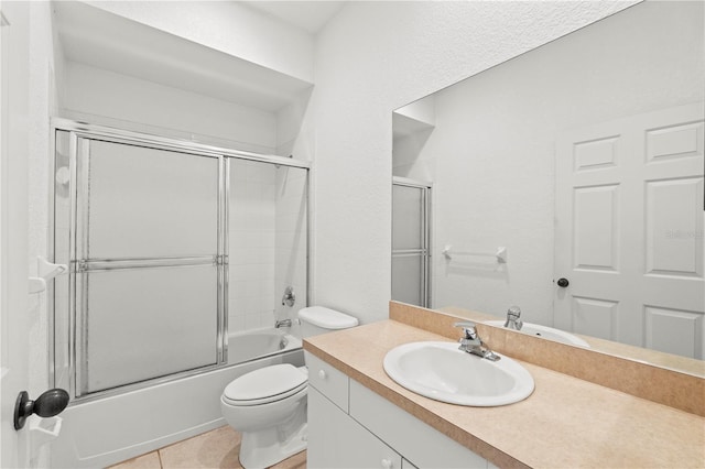 full bathroom with enclosed tub / shower combo, vanity, tile patterned floors, and toilet