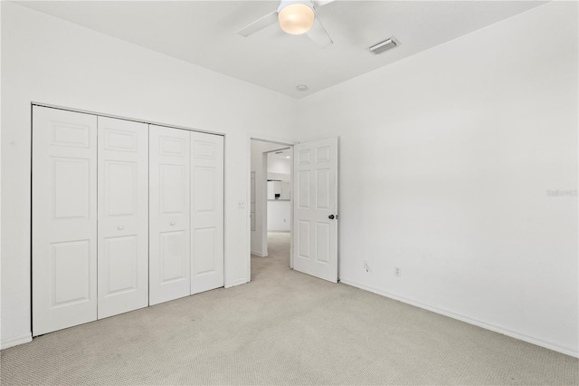 unfurnished bedroom featuring light carpet, a closet, and ceiling fan