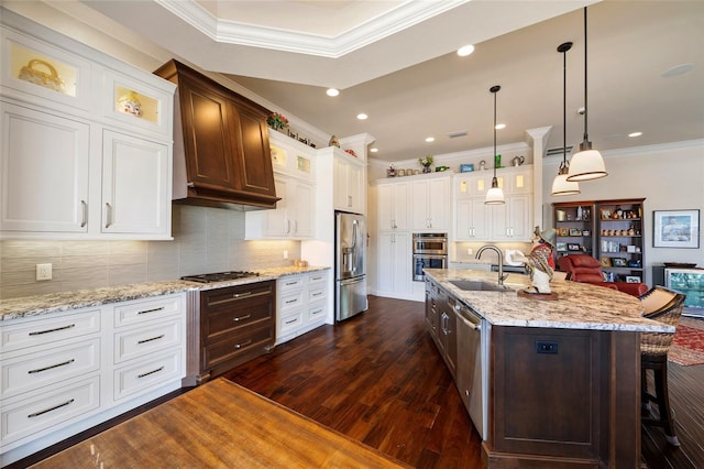 kitchen with appliances with stainless steel finishes, dark hardwood / wood-style floors, decorative light fixtures, an island with sink, and a kitchen bar