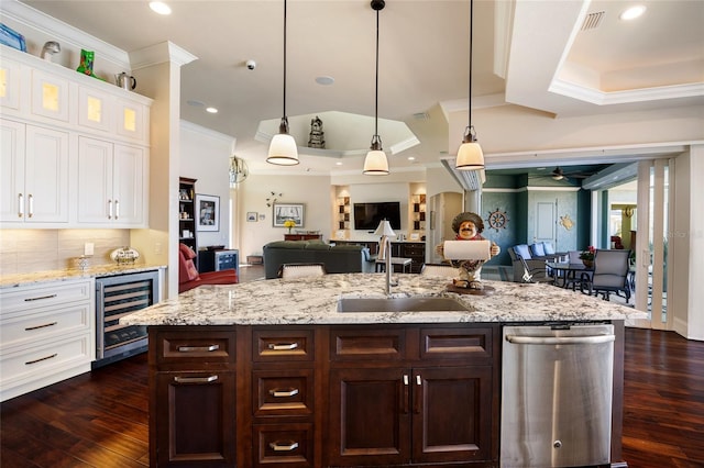 kitchen with white cabinetry, decorative light fixtures, stainless steel dishwasher, a raised ceiling, and beverage cooler